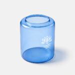 Blauer, zylindrischer Glas-Vorratstank mit offener Oberseite und weißem Lotusmotiv, schräg von vorn gezeigt.